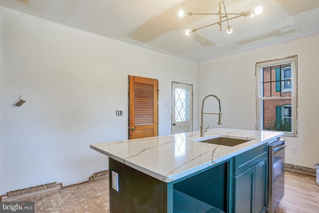 kitchen featuring light stone countertops, a center island with sink, light hardwood / wood-style flooring, a notable chandelier, and sink