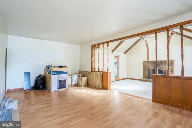 living room with ceiling fan, wood-type flooring, vaulted ceiling with beams, and a fireplace