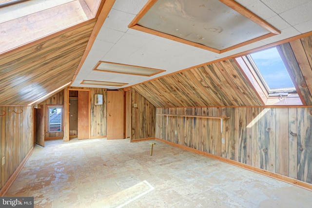 bonus room with plenty of natural light, wooden walls, and lofted ceiling with skylight