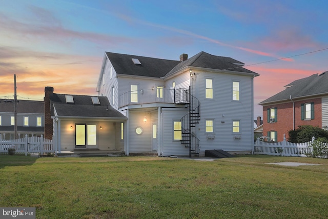 back house at dusk with a lawn