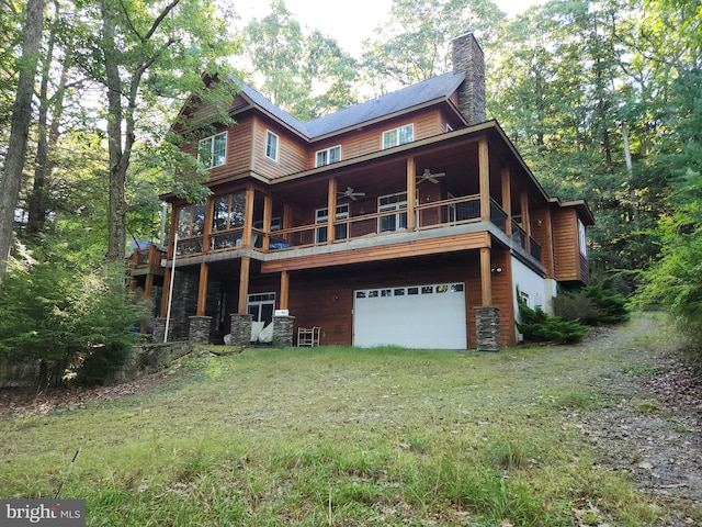 exterior space featuring a balcony, ceiling fan, a front yard, and a garage