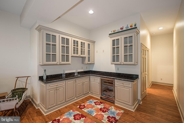 kitchen featuring dark stone countertops, beverage cooler, dark wood-type flooring, and gray cabinetry