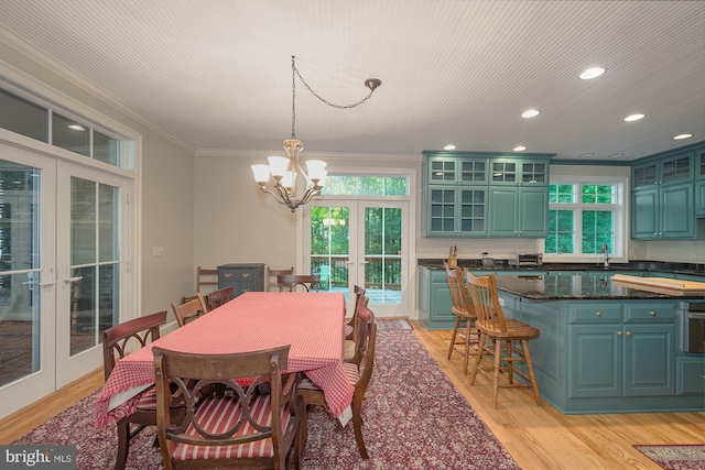 dining room featuring light wood-type flooring, french doors, ornamental molding, sink, and a chandelier