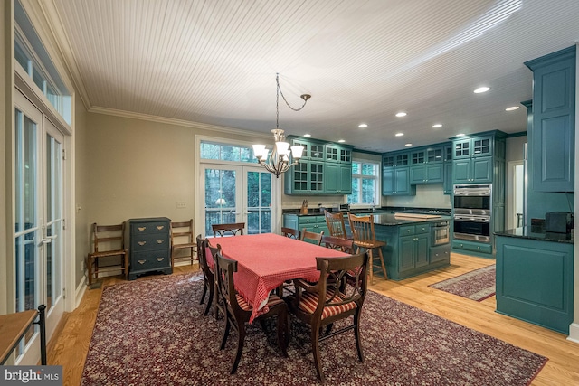 dining room with a healthy amount of sunlight, light hardwood / wood-style floors, ornamental molding, and a chandelier