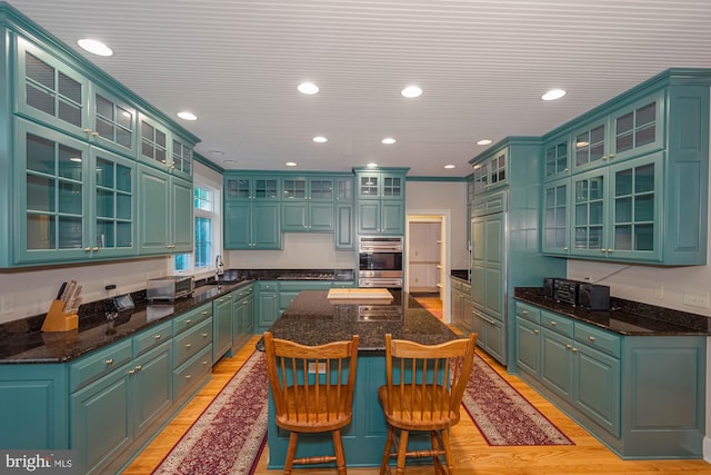 kitchen featuring light wood-type flooring, sink, a kitchen island, stainless steel appliances, and green cabinets