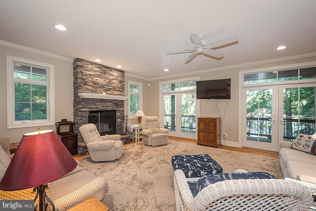 living room with a healthy amount of sunlight, a stone fireplace, ceiling fan, and french doors