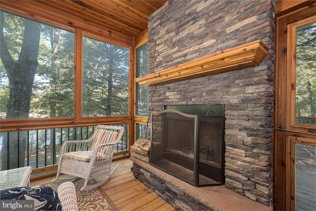 sunroom / solarium featuring wood ceiling, plenty of natural light, and a fireplace