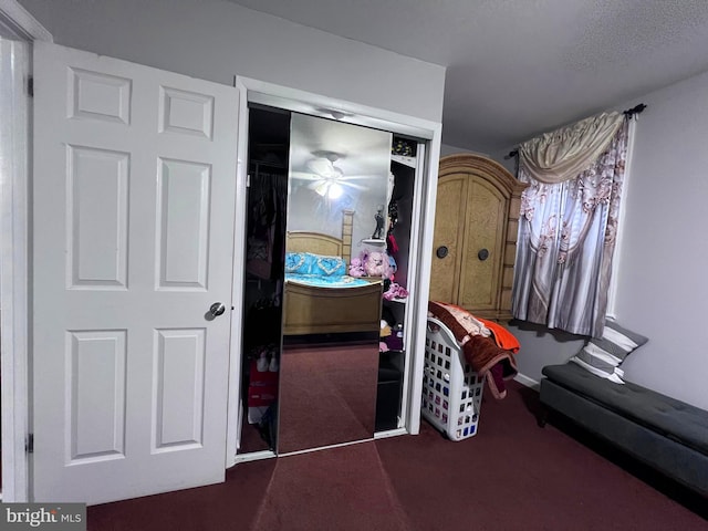 bedroom featuring a textured ceiling, dark colored carpet, and a closet