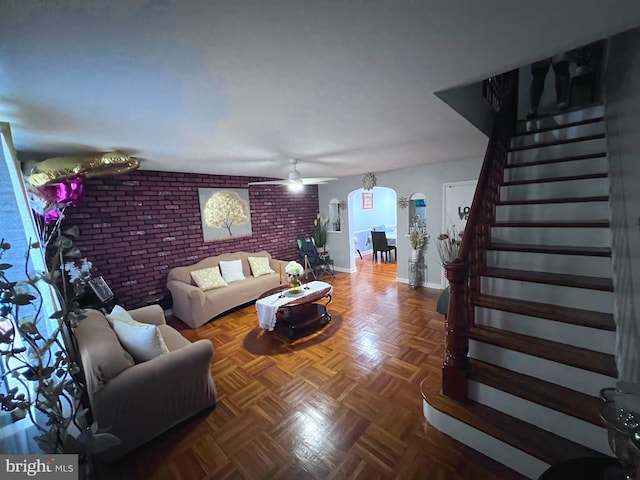 living room with brick wall, parquet floors, and ceiling fan