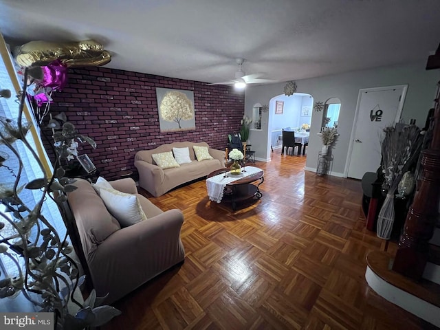 living room featuring brick wall, ceiling fan, and dark parquet flooring