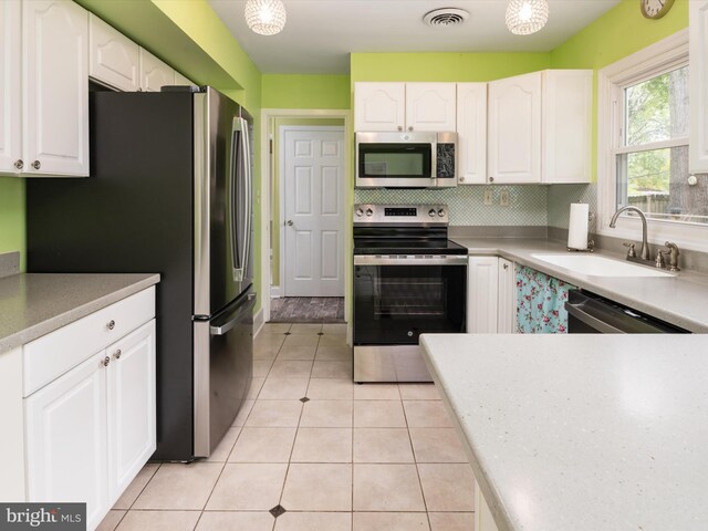 kitchen featuring white cabinetry, appliances with stainless steel finishes, sink, and light tile patterned floors