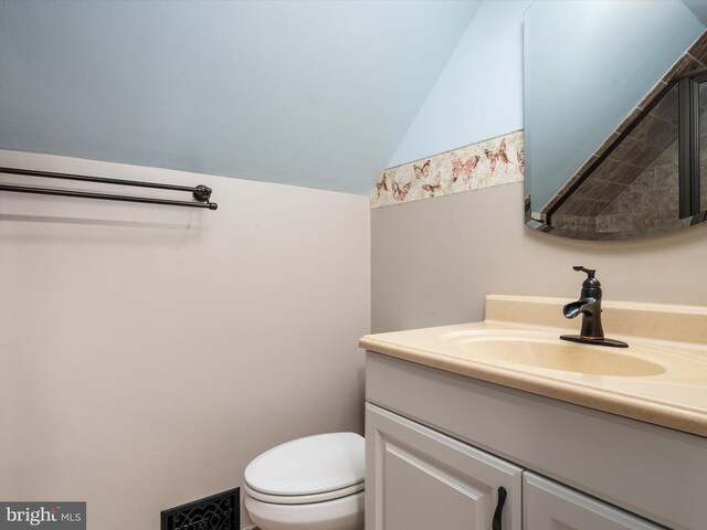 bathroom featuring lofted ceiling, vanity, and toilet