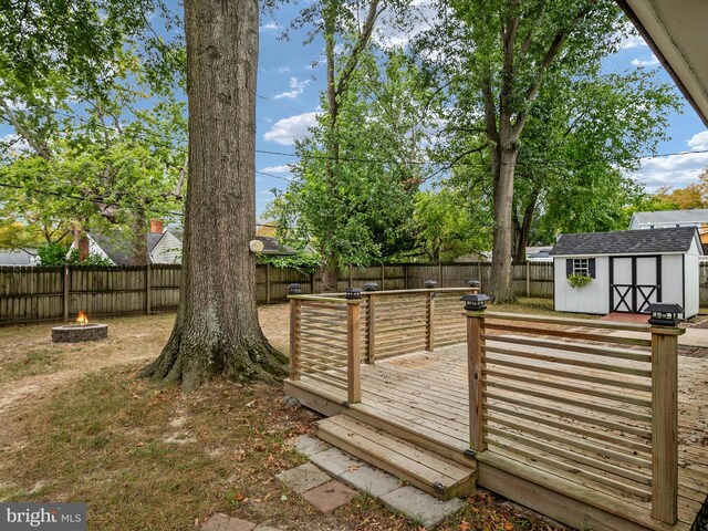 view of yard featuring a storage shed, a deck, and a fire pit