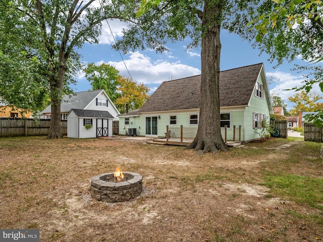 back of house with a storage shed, a yard, cooling unit, a deck, and a fire pit