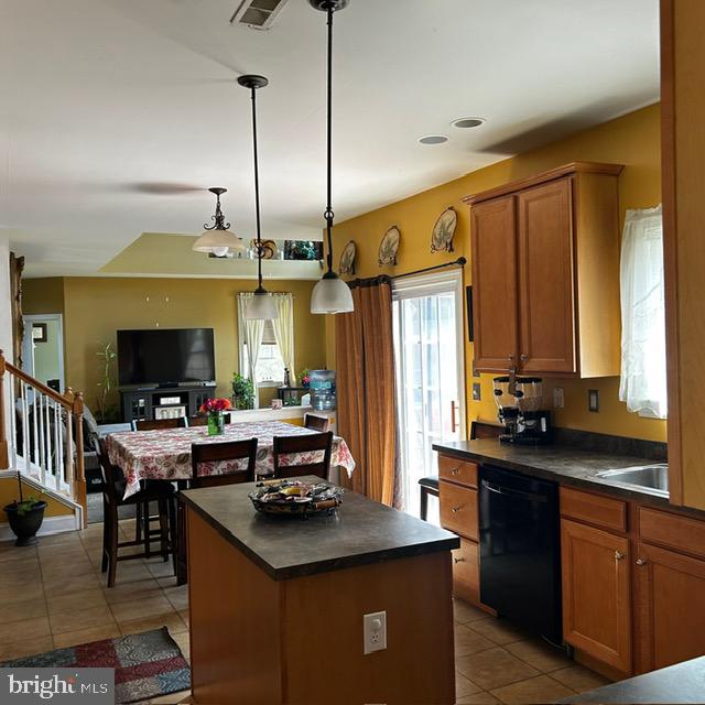 kitchen featuring dishwasher, a kitchen island, light tile patterned floors, and hanging light fixtures