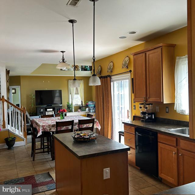 kitchen with light tile patterned floors, decorative light fixtures, a kitchen island, sink, and black dishwasher