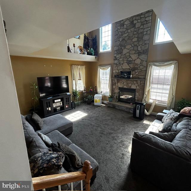 living room featuring a high ceiling, a fireplace, and carpet