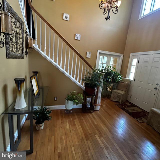 entryway featuring a towering ceiling, plenty of natural light, hardwood / wood-style floors, and a chandelier