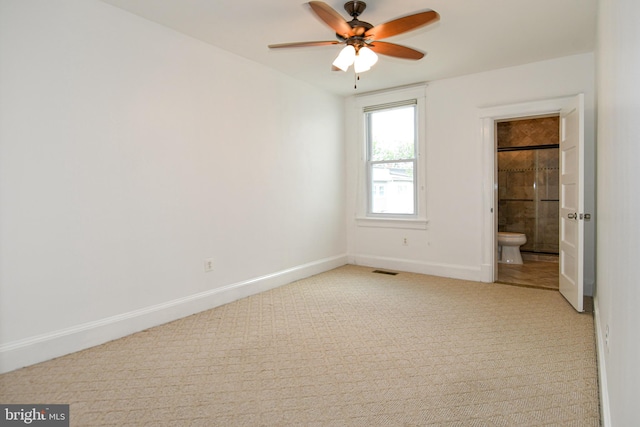 unfurnished bedroom with ceiling fan, ensuite bathroom, and light carpet