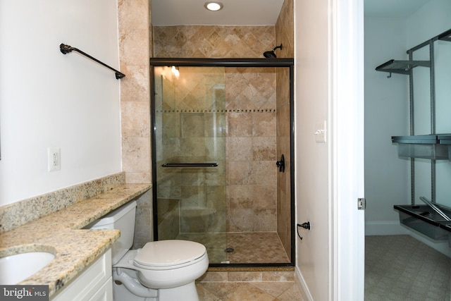 bathroom with a shower with door, vanity, and toilet