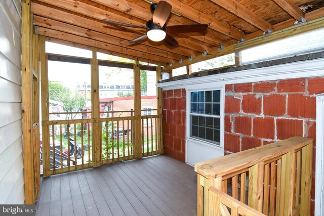 unfurnished sunroom featuring ceiling fan and beam ceiling