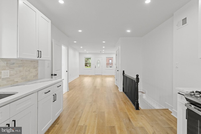 kitchen featuring light hardwood / wood-style flooring, light stone countertops, backsplash, and white cabinetry