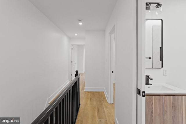 corridor featuring light wood-type flooring and sink