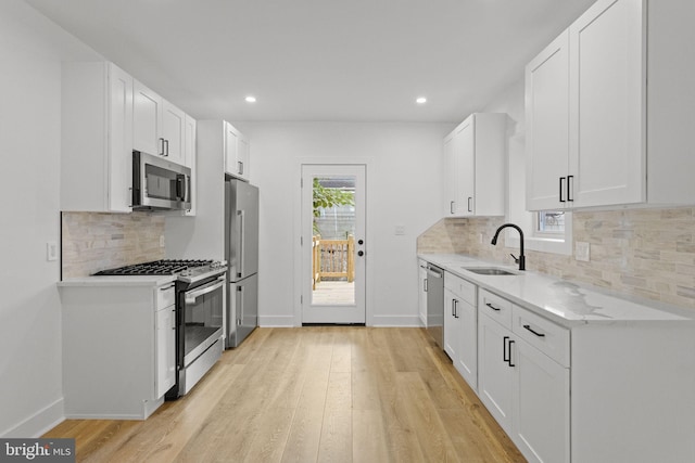 kitchen featuring appliances with stainless steel finishes, sink, white cabinets, and light hardwood / wood-style floors