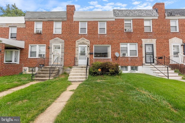 multi unit property featuring brick siding, cooling unit, and a front yard