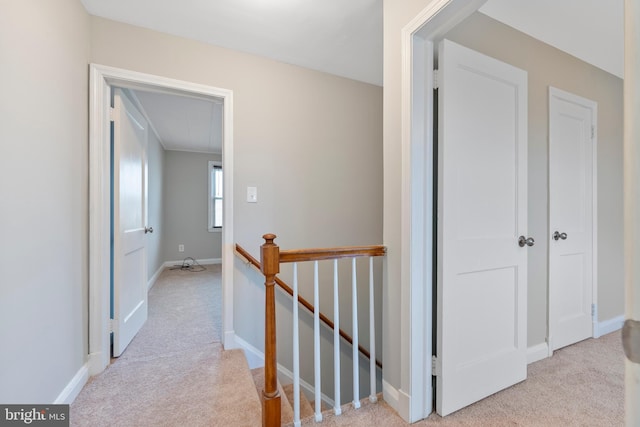 hall featuring baseboards, an upstairs landing, attic access, and carpet flooring