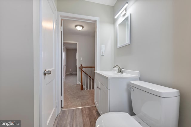 half bath with toilet, wood finished floors, and vanity