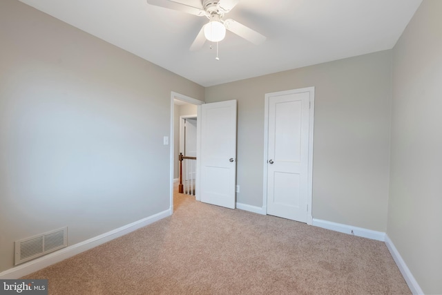 unfurnished bedroom with ceiling fan, baseboards, visible vents, and light carpet