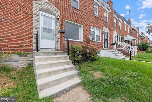 property entrance featuring a lawn and brick siding