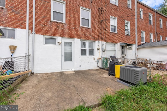 rear view of property with brick siding, cooling unit, and fence
