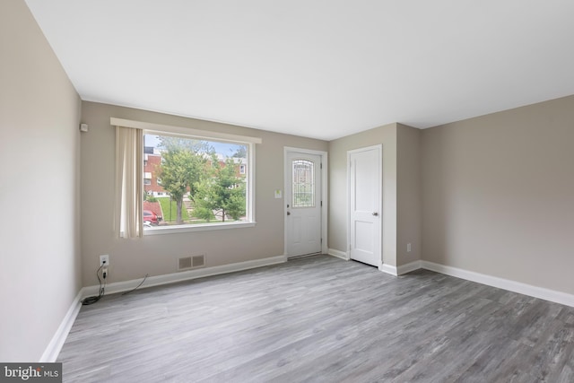 unfurnished room featuring wood finished floors, baseboards, and visible vents