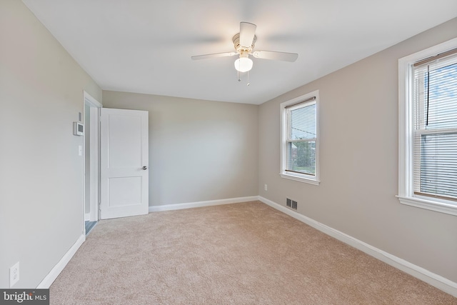 unfurnished room featuring visible vents, plenty of natural light, light colored carpet, and baseboards