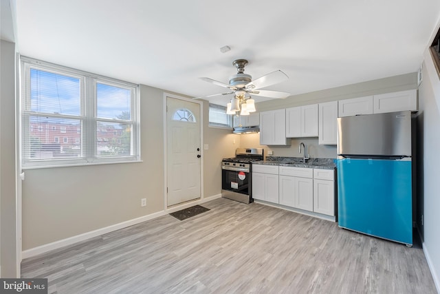 kitchen featuring baseboards, under cabinet range hood, light wood-style flooring, stainless steel appliances, and a ceiling fan