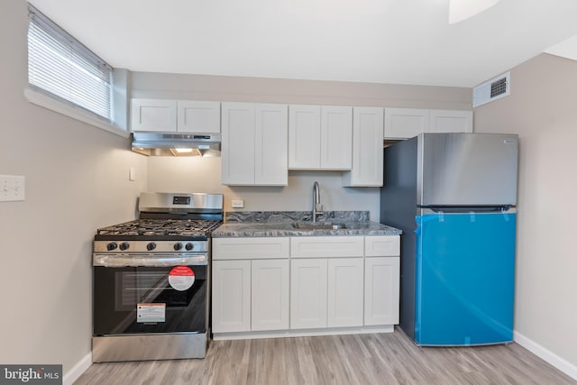 kitchen with visible vents, light wood-type flooring, under cabinet range hood, a sink, and appliances with stainless steel finishes