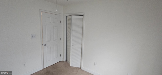 unfurnished bedroom with light colored carpet and a closet