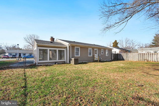 back of house with central air condition unit and a yard