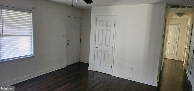 unfurnished bedroom with multiple windows, ceiling fan, and dark wood-type flooring