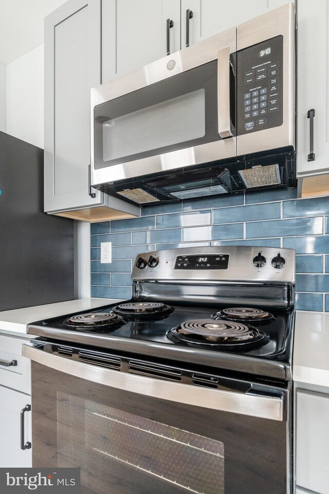 kitchen featuring stainless steel appliances, decorative backsplash, and white cabinetry