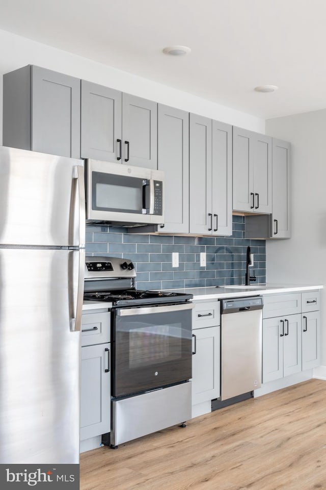 kitchen with backsplash, stainless steel appliances, and light hardwood / wood-style flooring