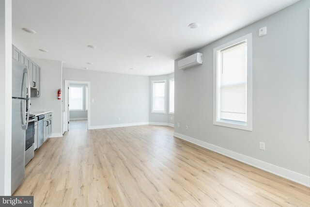 unfurnished living room with an AC wall unit and light hardwood / wood-style floors