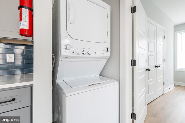 washroom featuring light wood-type flooring and stacked washer / drying machine