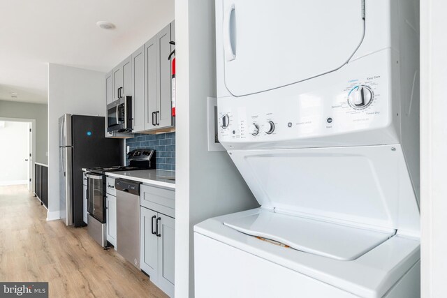 washroom featuring stacked washing maching and dryer and light hardwood / wood-style floors