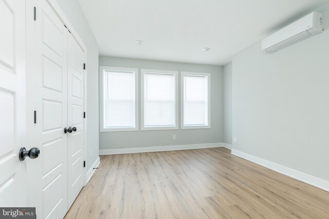 empty room featuring light hardwood / wood-style flooring and an AC wall unit