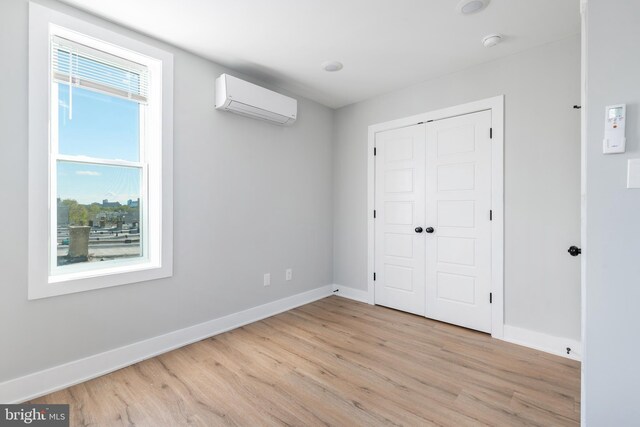 interior space featuring light wood-type flooring, a closet, and a wall unit AC