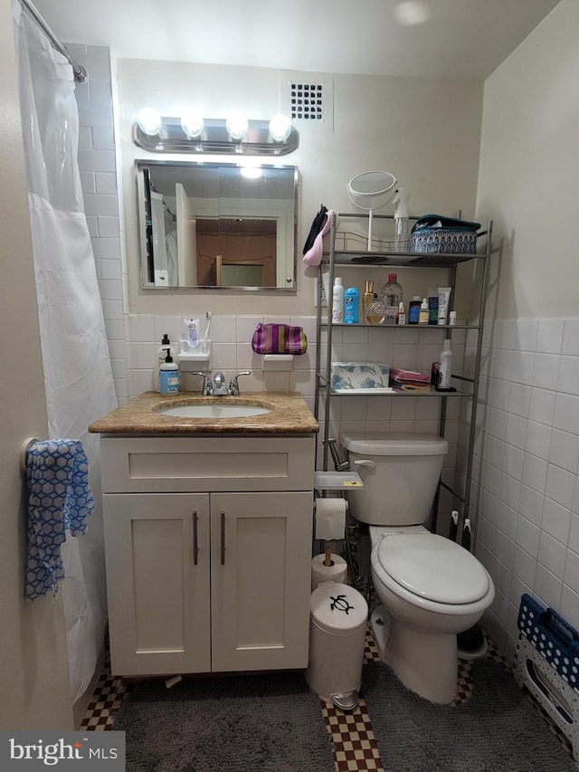 bathroom featuring tile walls, walk in shower, tile patterned floors, vanity, and toilet