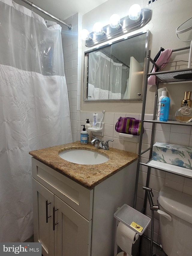 bathroom with tile walls, tasteful backsplash, curtained shower, vanity, and toilet